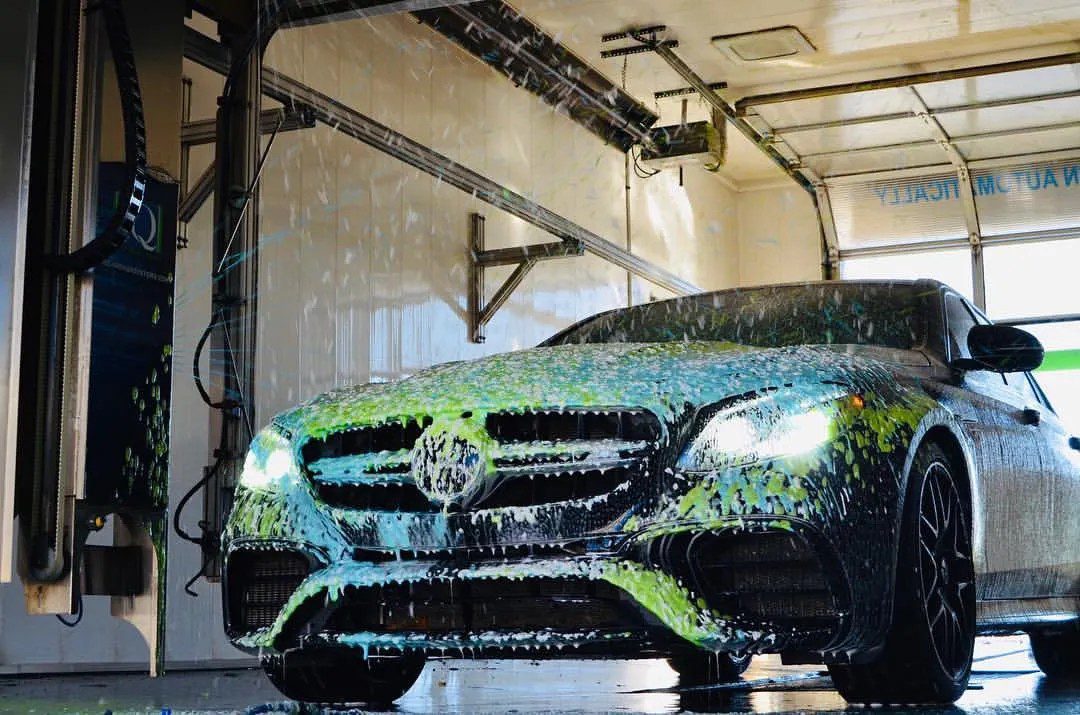 CarWashSoap.com <strong> Powered by </strong> ChemQuest A black SUV is being sprayed with blue water jets inside an automated car wash bay.