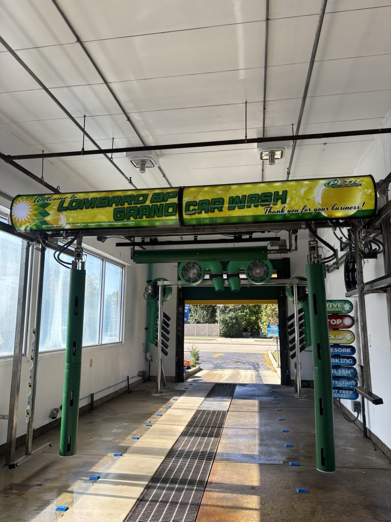 The interior of an automated car wash bay with a prominent overhead sign reading “Lombard BP Grand Car Wash.”