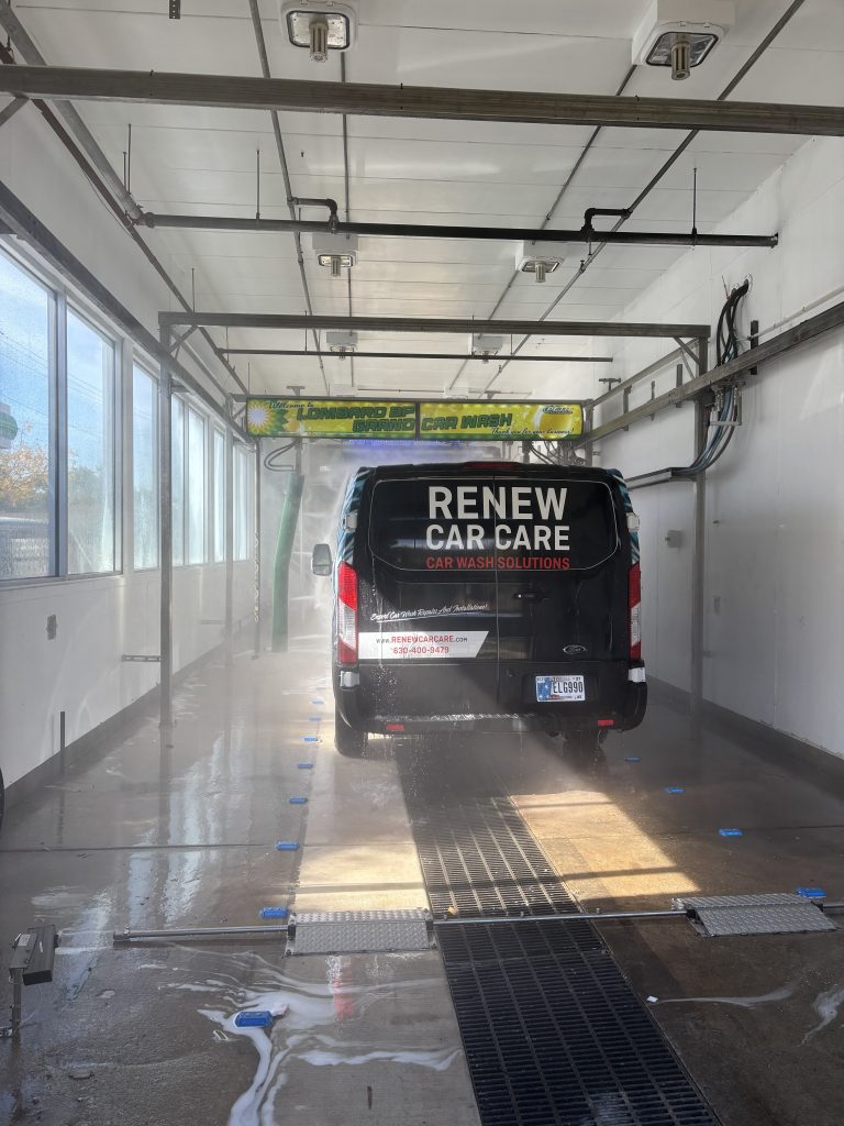 A black van branded “Renew Car Care” being washed inside an automated car wash bay.
